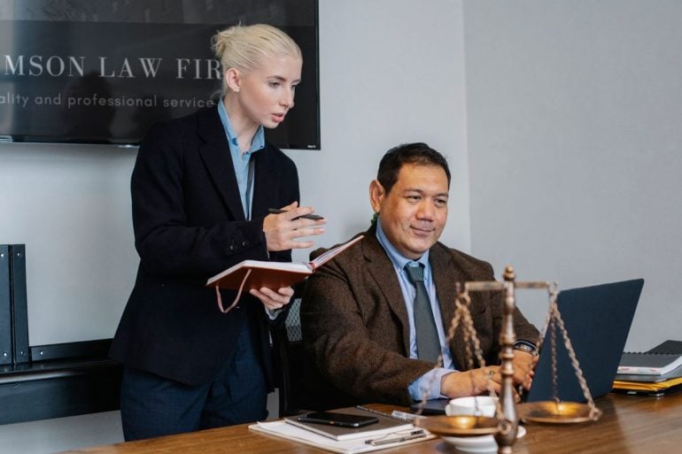 Lawyer showing a document on a laptop to a colleague
