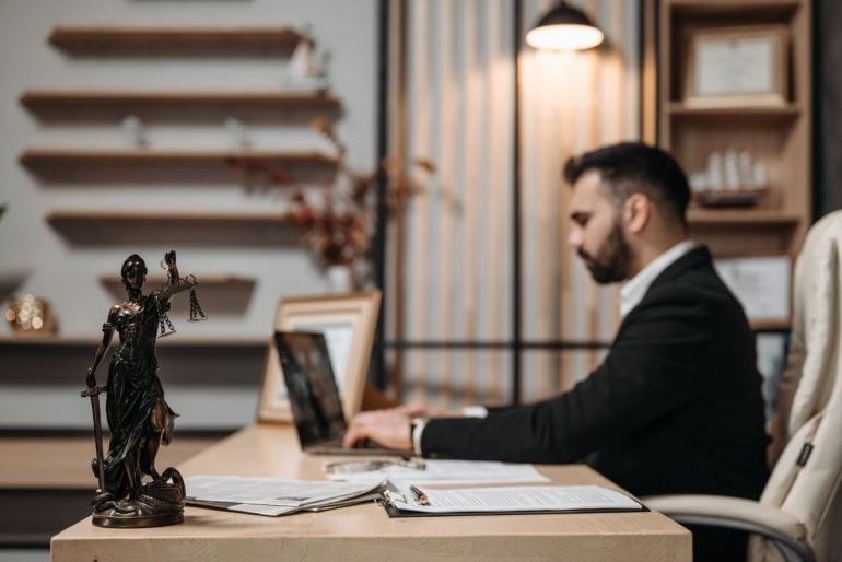 Man in a suit jacket working on a laptop
